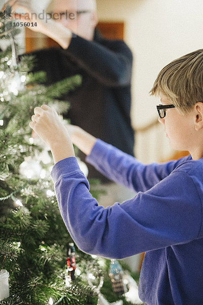 Eine Person  die zu Hause einen Weihnachtsbaum schmückt.