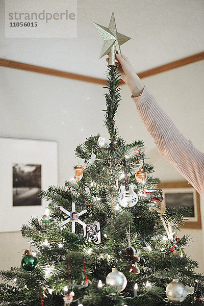 Eine Person  die zu Hause einen Weihnachtsbaum schmückt.