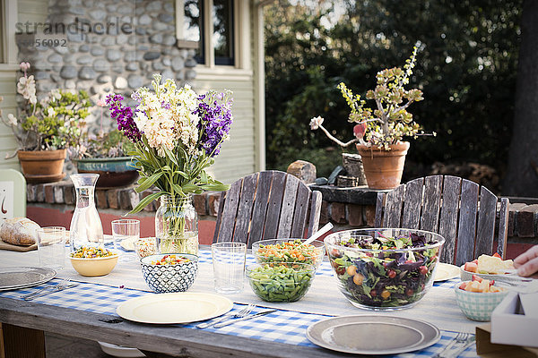 Ein gedeckter Tisch für eine Mahlzeit im Freien in einem Garten.
