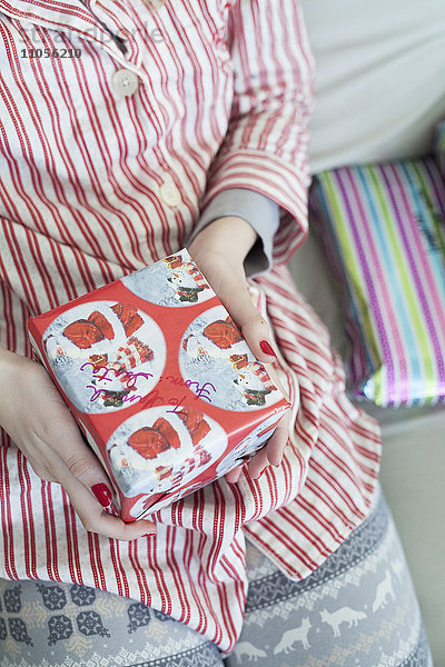 Ein Mädchen hält ein kleines eingepacktes Weihnachtsgeschenk in der Hand.