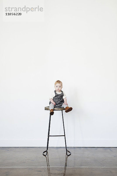 Ein kleines Kind  ein kleines Mädchen  das lachend auf einem hohen Hocker sitzt.