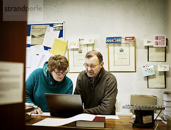 Zwei Personen an einem Computer in einem kleinen Buchbindereibetrieb.