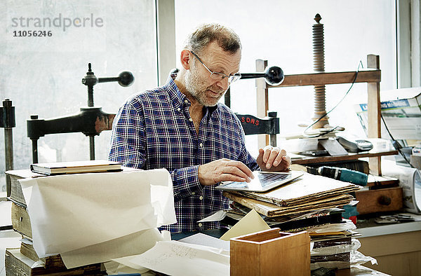 Ein Mann benutzt ein digitales Tablett in einer Buchbinderei.