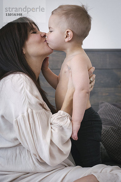 Eine hochschwangere Frau küsst ihren kleinen Sohn.