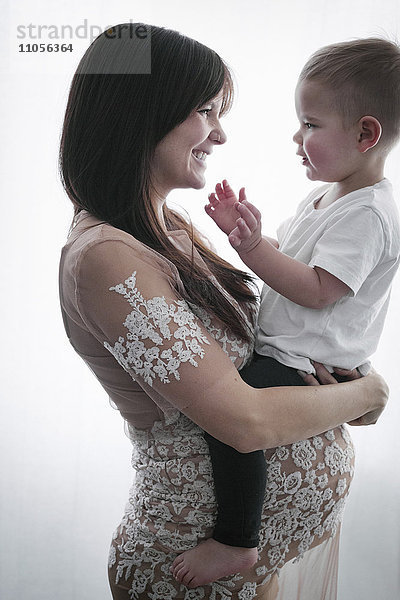 Eine schwangere Frau hält ihren kleinen Sohn im Arm.