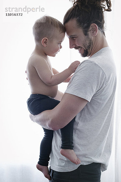 Ein junger Mann  der ein kleines Kind in seinen Armen hält.