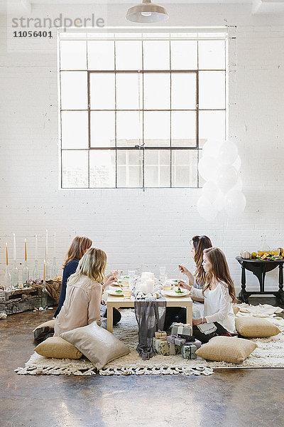 Vier Frauen saßen an einem niedrigen Tisch auf Kissen.