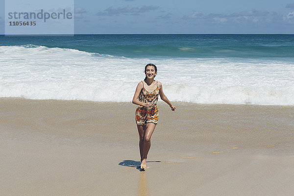 Glückliche Dreizehnjährige laufen den Strand hinauf