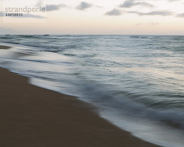 Meereslandschaft und brechende Wellen am Strand in der Abenddämmerung.