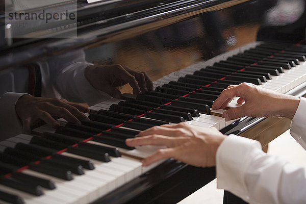 Nahaufnahme der Hände eines Pianisten  der auf einem Flügel spielt.
