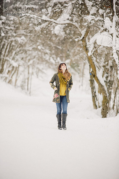 Eine Frau  die im Schnee im Wald spazieren geht.
