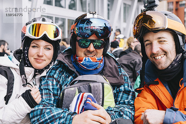 Drei Personen  eine junge Frau und zwei Männer in Skiausrüstung  in einer Reihe auf Skiurlaub.
