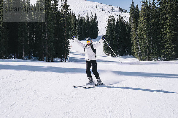 Ein Skifahrer  eine junge Frau am Himmel mit ausgestreckten Armen  auf der Piste.