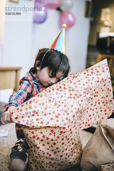 Ein Junge packt auf einer Geburtstagsfeier Geschenke aus.