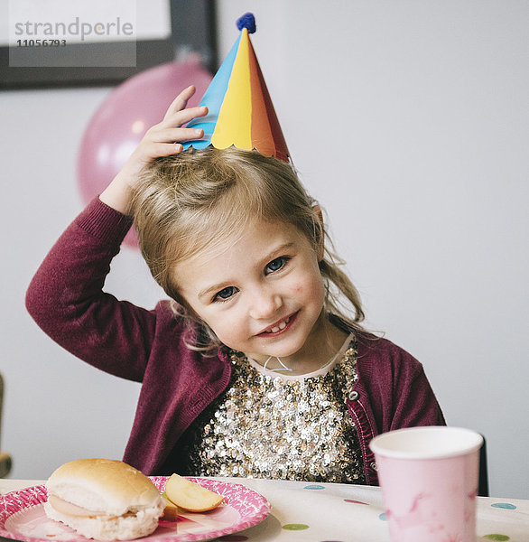 Ein junges Mädchen mit Partyhut auf einer Geburtstagsfeier.
