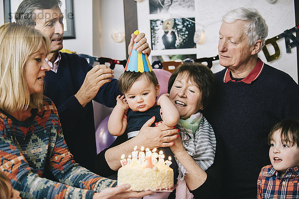 Eine Familie versammelte sich  um den Geburtstag eines einjährigen Mädchens zu feiern. Ein Kuchen mit vielen Kerzen.