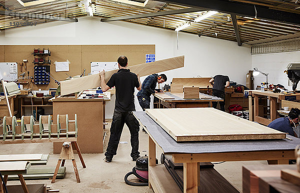 Eine Möbelwerkstatt  die maßgeschneiderte zeitgenössische Möbelstücke unter Verwendung traditioneller Fertigkeiten herstellt. Zwei Männer arbeiten mit Holz