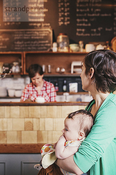 Zwei Frauen  ein gleichgeschlechtliches Paar mit ihrem 6 Monate alten Baby in ihrem Café. Geschäftsinhaber und Eltern.