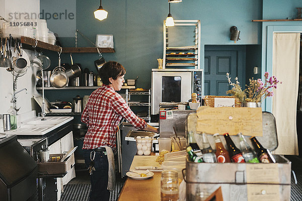 Eine Frau  die in einem Café hinter der Theke arbeitet.