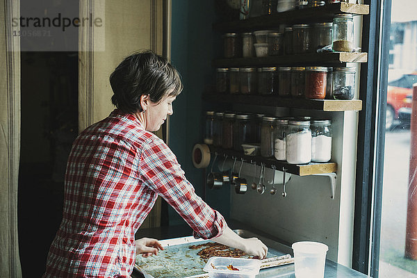 Eine Frau mit einem Tablett mit gekochtem Speck in einer Coffee-Shop-Küche.