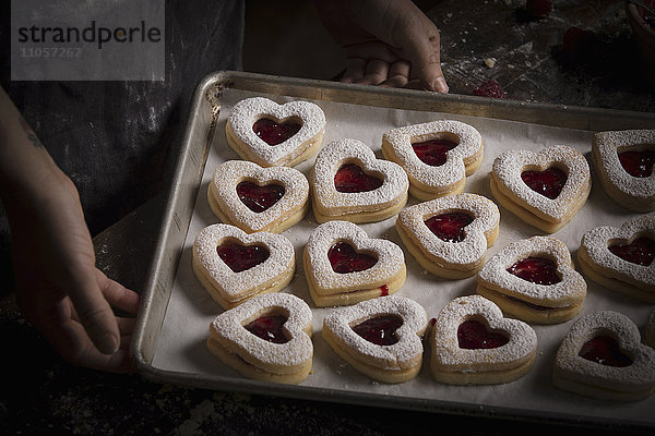 Valentinstag-Backen  Hochwinkelansicht eines Backblechs mit herzförmigen Keksen.