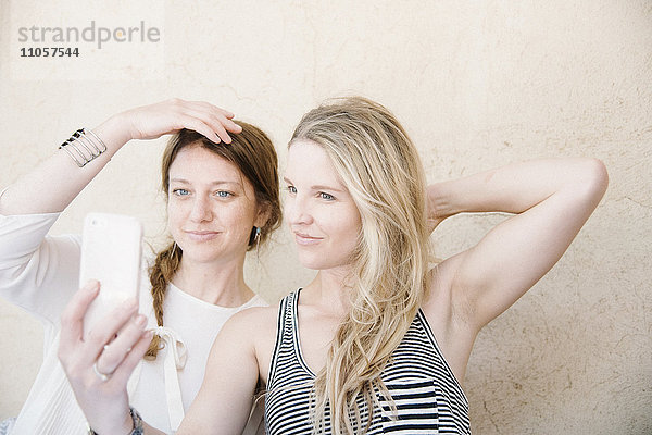 Zwei lächelnde Frauen beim Selfie mit dem Handy.