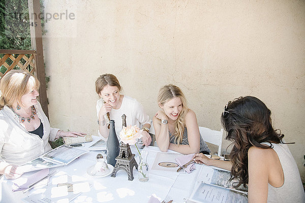 Vier Frauen sitzen an einem Tisch  lächeln und plaudern.