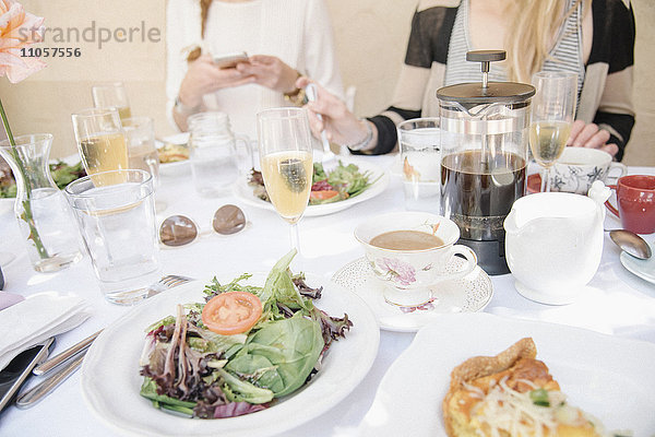 Schrägansicht auf einen Tisch mit Speisen und Getränken  Tellern mit Omelett und Salat  Kaffee und Champagner.