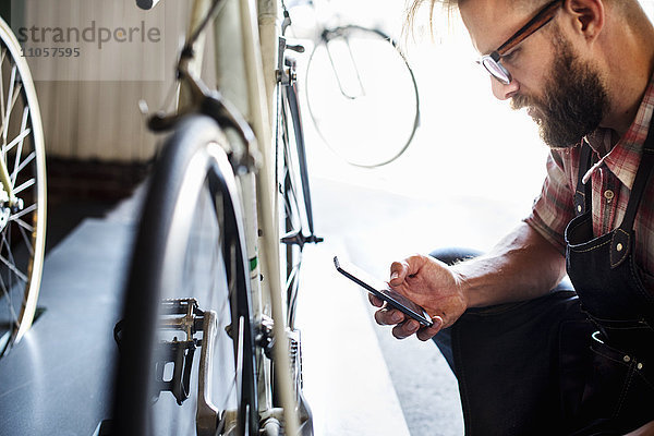 Ein Fahrradmechaniker in einer Fahrradwerkstatt mit einem Smartphone.