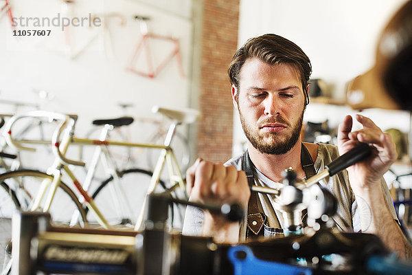 Ein Mann  der in einer Fahrradwerkstatt arbeitet und den Rahmen des Fahrrads überprüft.