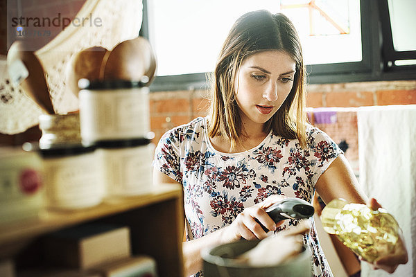 Junge Frau in einem Geschäft  die den Strichcode eines Trinkglases mit einem Strichcode-Scanner einscannt.