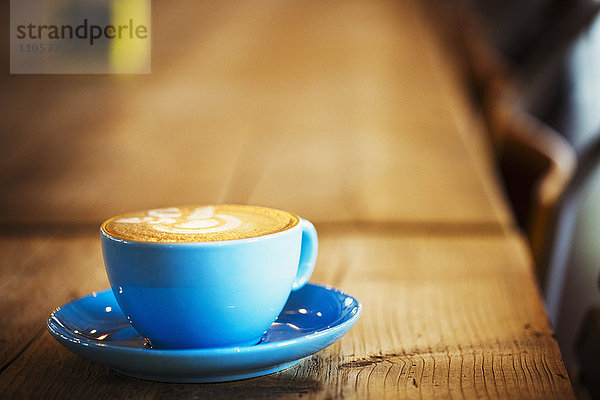 Spezialisiertes Kaffeehaus. Tasse und Untertasse aus blauem Porzellan mit schaumigem Kaffee.