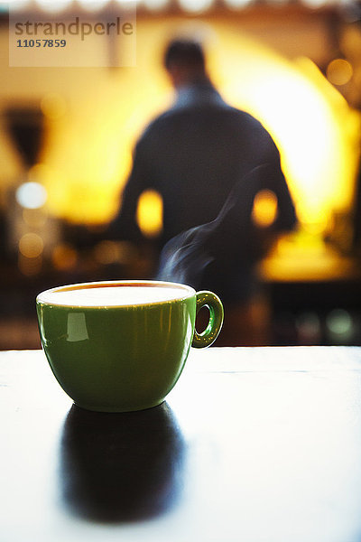 Spezialisiertes Kaffeehaus. Eine Tasse Kaffee auf einer Theke mit schaumiger Oberfläche.