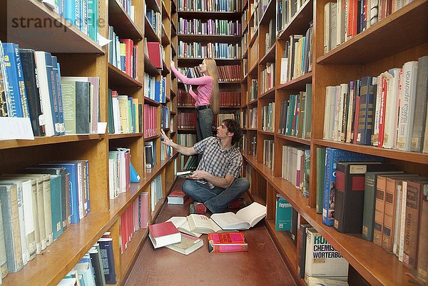 Studenten zwischen Bücherregalen in Universitätsbibliothek