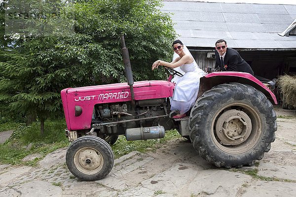 Brautpaar fährt auf Traktor