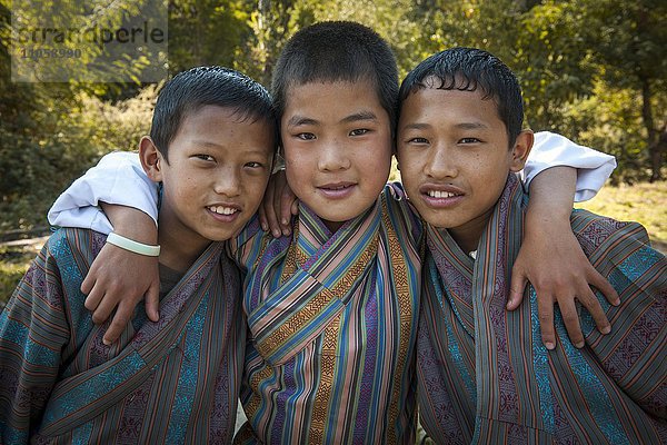 Drei Jungen mit traditioneller Kleidung  Punakha  Himalaya-Region  Königreich Bhutan