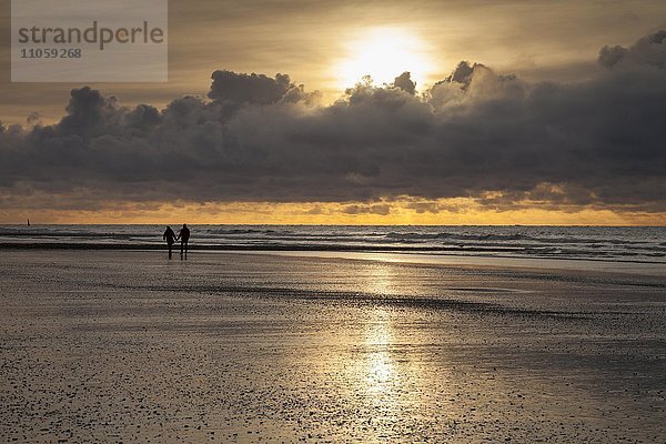Spaziergänger an der Küste  Abendlicht  Sonnenuntergang mit Wolken  Norderney  Ostfriesische Insel  Ostfriesland  Niedersachsen  Deutschland  Europa
