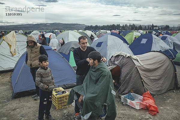 Flüchtlingslager Idomeni an der griechisch-mazedonischen Grenze  Friseur schneidet Flüchtling die Haare  Idomeni  Zentralmakedonien  Griechenland  Europa
