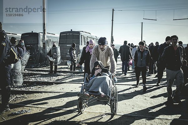 Flüchtlinge und alte Frau im Rollstuhl am Grenzzaun  Flüchtlingslager Idomeni  Grenze zu Mazedonien  Griechenland  Europa
