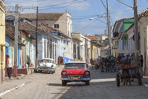 Straßenszene  typische Straße mit Kopfsteinpflaster  bunte Häuser und Oldtimer  historische Altstadt  Trinidad  Provinz Sancti Spiritus  Kuba  Nordamerika
