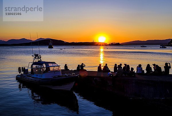 Silhouette von Jugendlichen am Wasser  betrachten den Sonnenuntergang  Oban  Argyll and Bute  Schottland  Vereinigtes Königreich