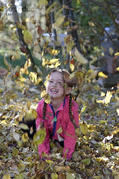 Kind  Mädchen spielt mit Laub  Herbstblätter  Bayern  Deutschland  Europa