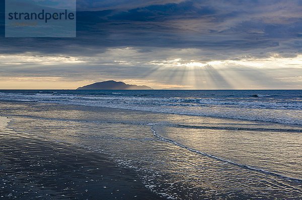 Abendstimmung am Sandstrand  Wellen  Sonnenstrahlen mit dramatischem Wolkenhimmel  Ostküste  Nordinsel  Neuseeland  Ozeanien
