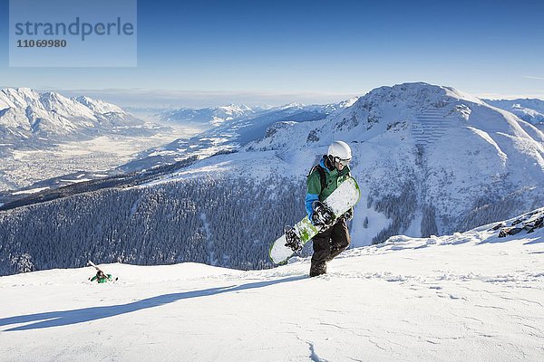 Snowboardfahrer beim Aufstieg mit Blick auf Innsbruck und Inntal  Axamer Lizum  Tirol  Österreich  Europa