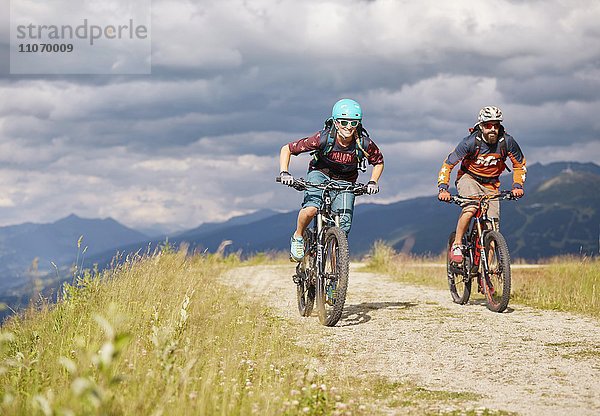 Zwei Mountainbiker mit Helm fahren auf einem Schotterweg  Mutterer Alm bei Innsbruck  Patscherkofel  Tirol  Österreich  Europa