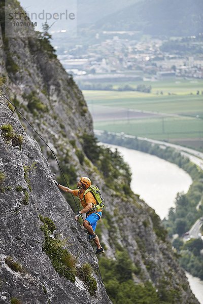 Bergsteiger  Kletterer mit orangen Helm beim Aufstieg am Klettersteig  Zirl  Innsbruck  Tirol  Österreich  Europa