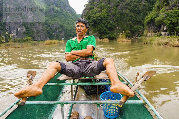 Einheimischer Mann rudert mit den Füßen  auf dem Ngô ng-Fluss  sông Ngô ng  Tam Coc  Ninh Bình  Vietnam  Asien