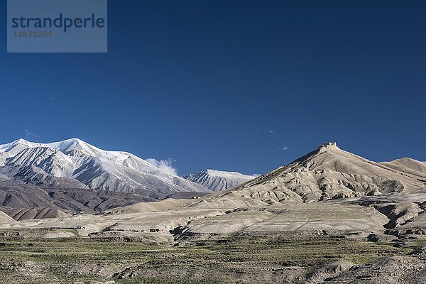 Schneebedeckte Berge und Ruine  Berglandschaft bei Lo Manthang  Königreich Mustang  Upper Mustang  Himalaya  Nepal  Asien