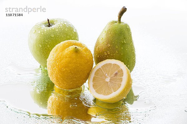 Apfel  Birne und Zitrone mit Wassertropfen spiegeln sich