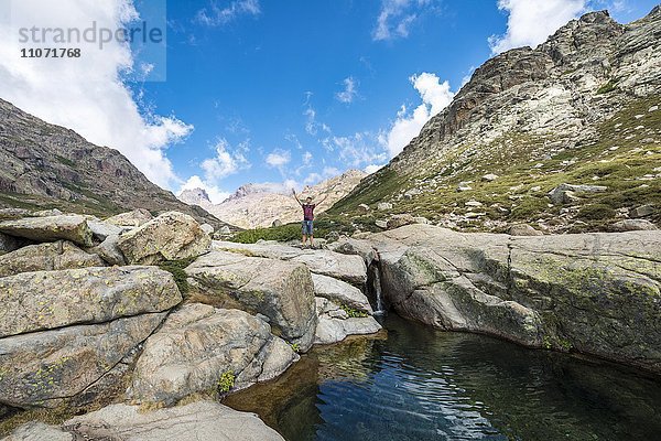 Junger Mann steht an kleinem Wasserfall mit Gumpe  Gebirgslandschaft  Fluss Golo  Regionaler Naturpark Korsika  Parc naturel régional de Corse  Korsika  Frankreich  Europa